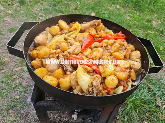 Картопля з куркою на пательні (сковороді, саджі) на вогні, приготування